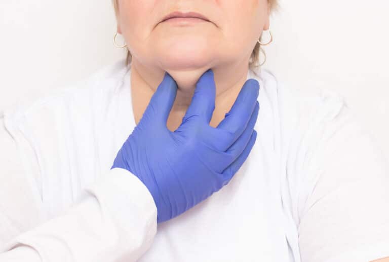 Gloved hand on medical professional assessing fat under woman's chin