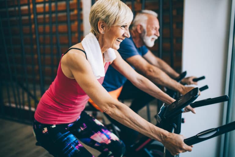 Fit older couple working out on bicycles with energy after B12 shots